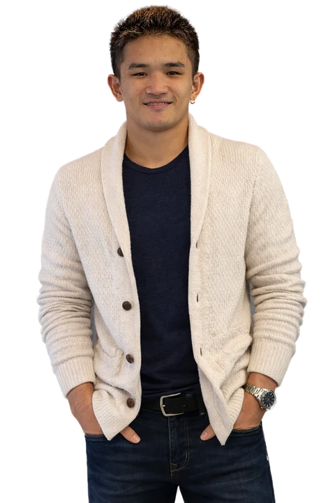 Kurt in a cream cardigan over a navy T-shirt, hands in his pockets, shown as a cutout.